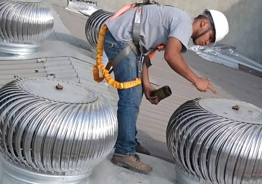 técnico instalando exaustores eólicos em telhado